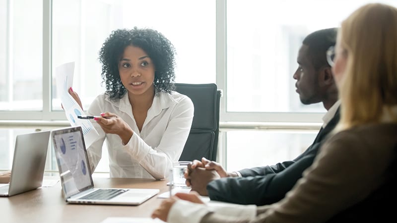 Mitarbeiter diskutieren über gedrucktes Tabellenblatt Mitarbeiter diskutieren über gedrucktes Tabellenblatt